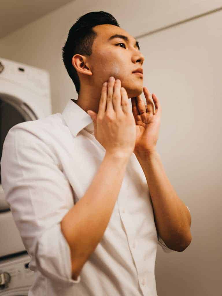 A man applying lotion to his face.