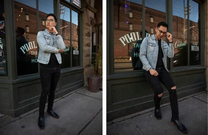 A man with glasses wearing a denim jacket with black jeans.