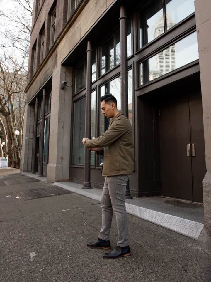 Person standing on sidewalk and checking the time on their watch.