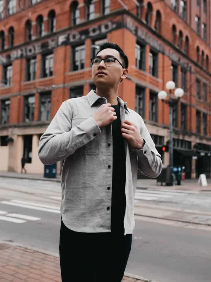 Person standing on a sidewalk in front of a brick building.