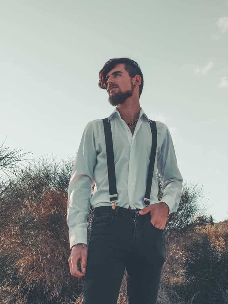 A man wearing suspenders with one hand in his pocket.