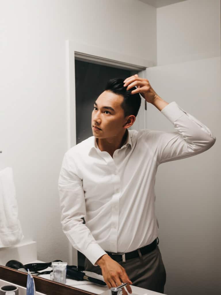 Person in bathroom styling hair.