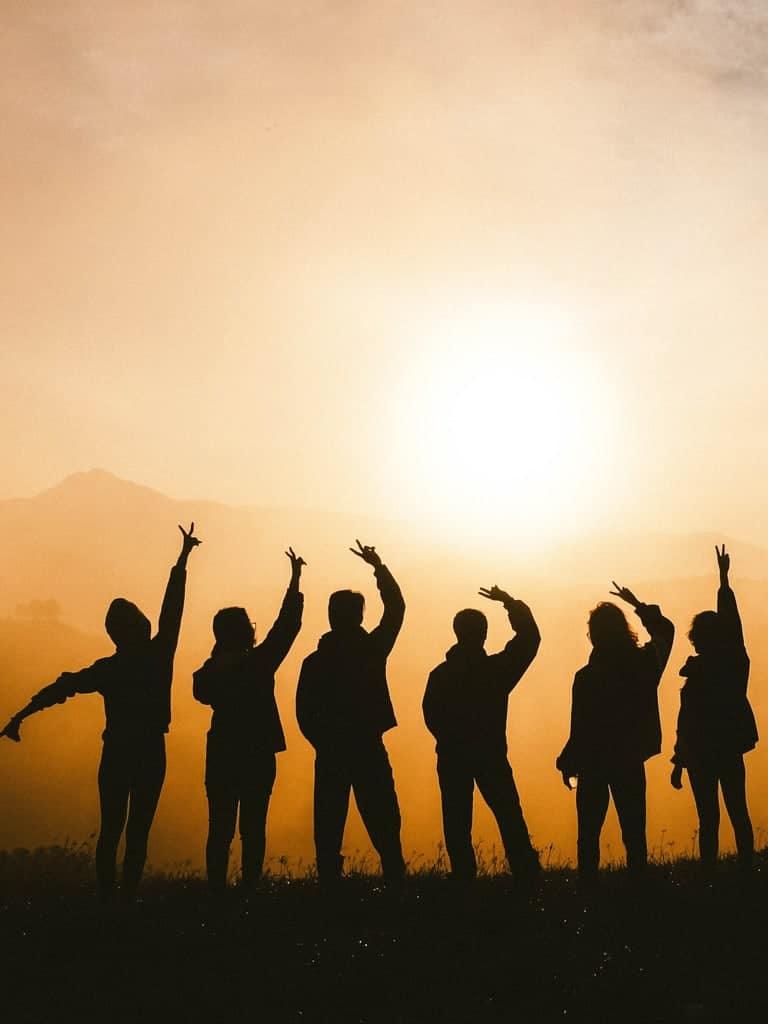 Silhouette of a group with their hands up.