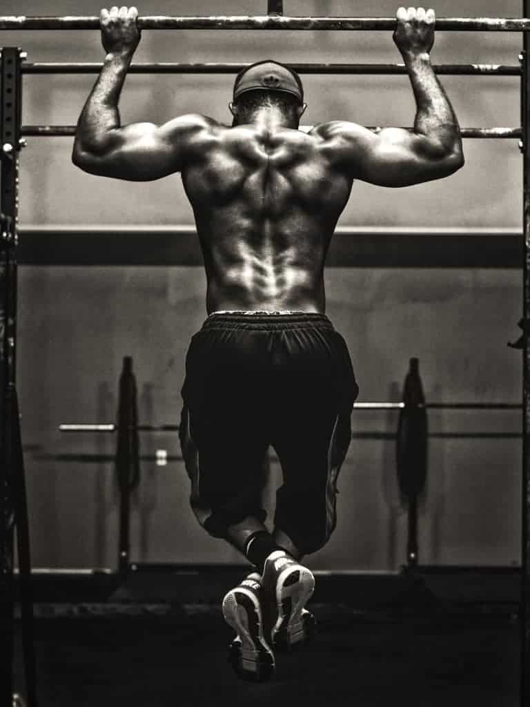 A grayscale image of a man doing a pull-up.