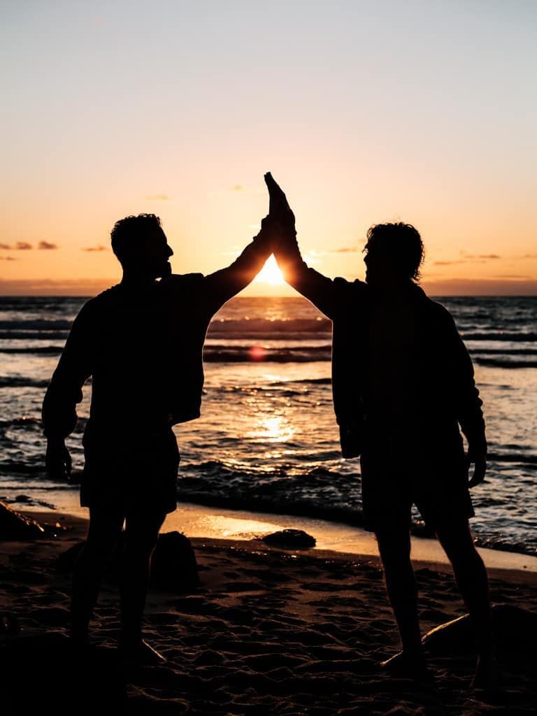 Silhouette of two men giving each other a high-five.
