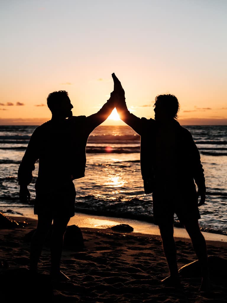 Silhouette of two people giving each other a high-five.