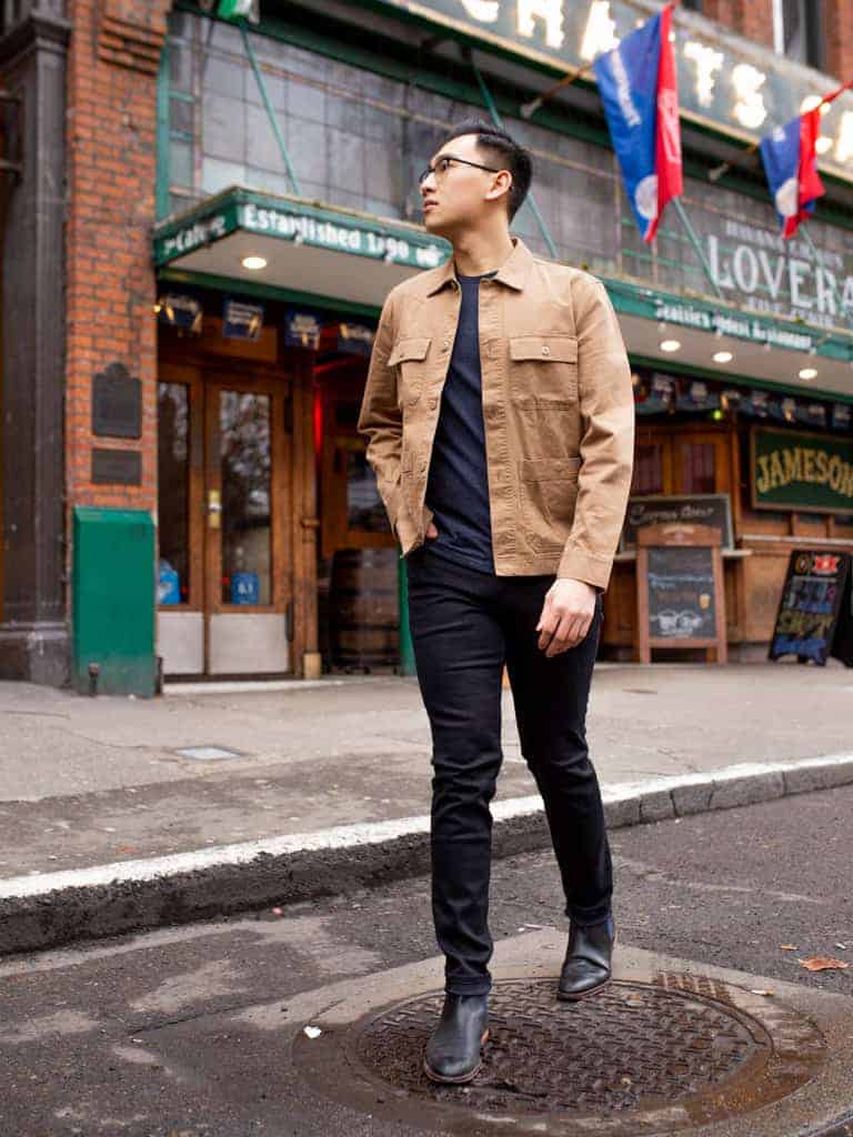 Man in khaki jacket walking on the road.