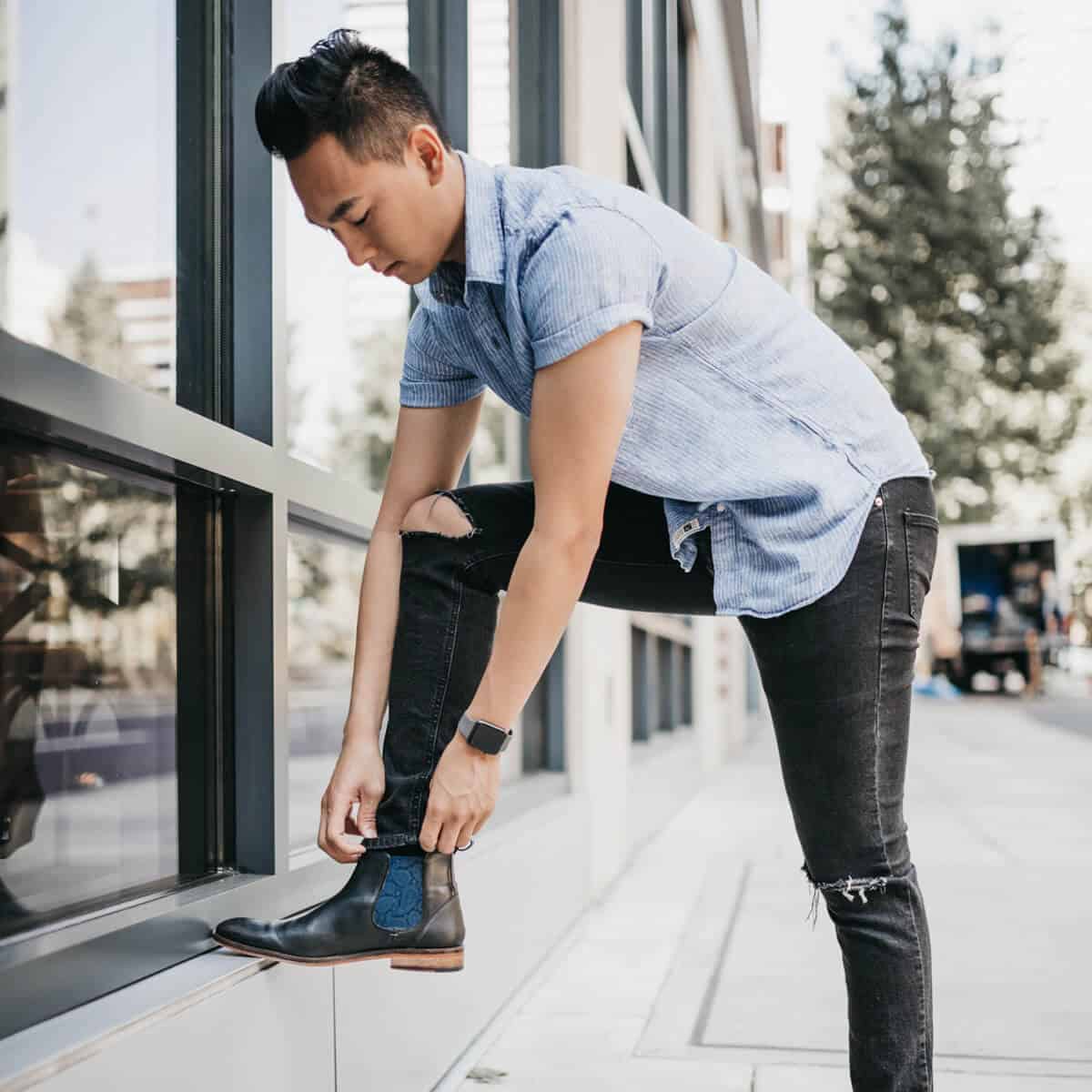 Person wearing Chelsea boots with their foot on a ledge.