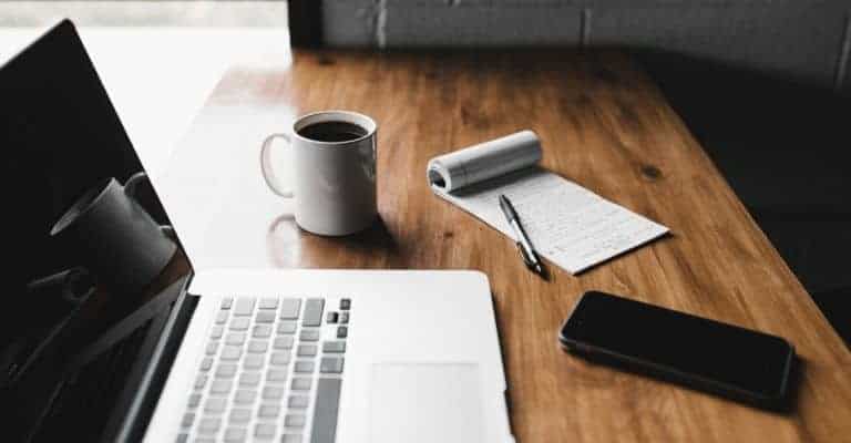 Electronics and coffee mug on wooden table.