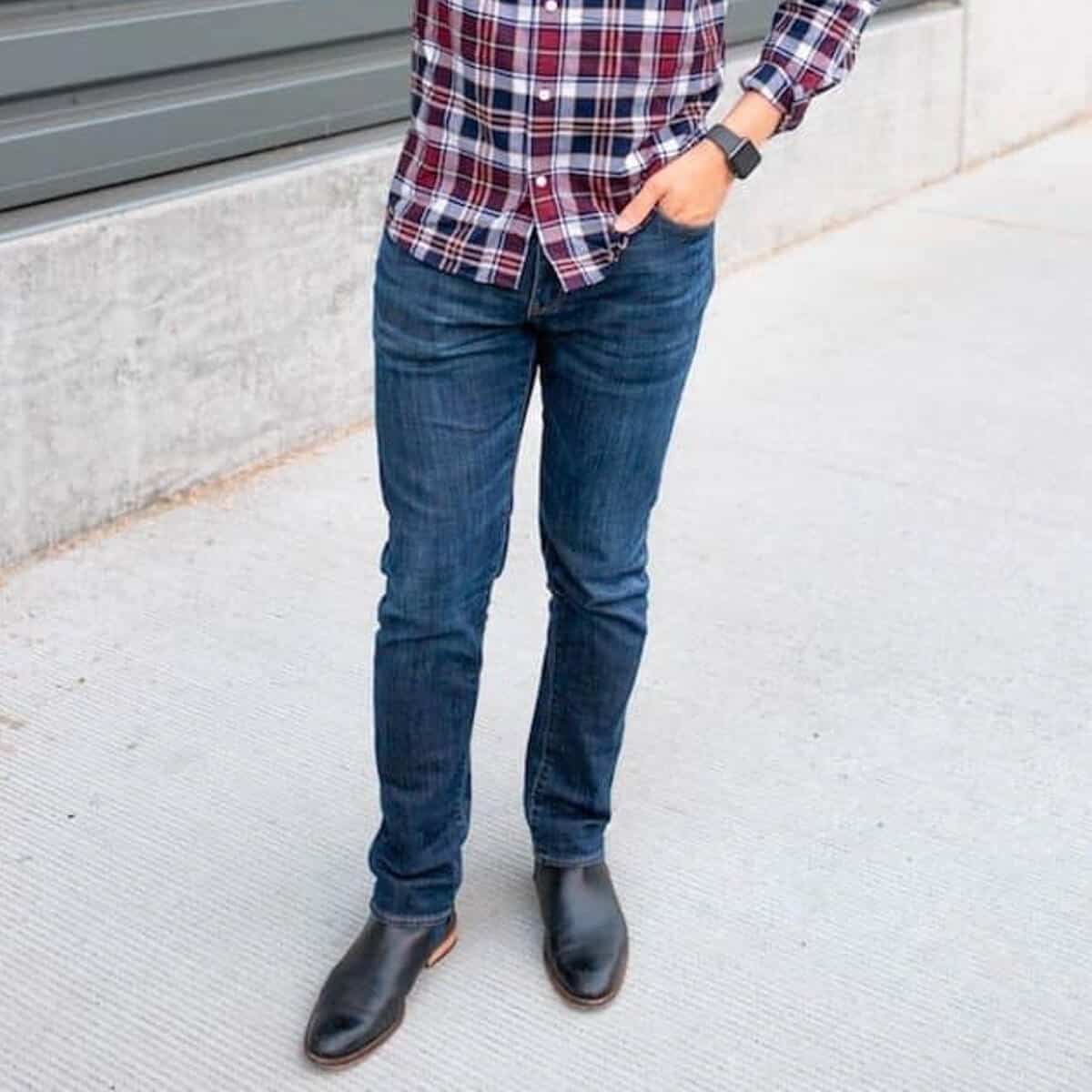 Person standing near a wall with a hand in their pocket.