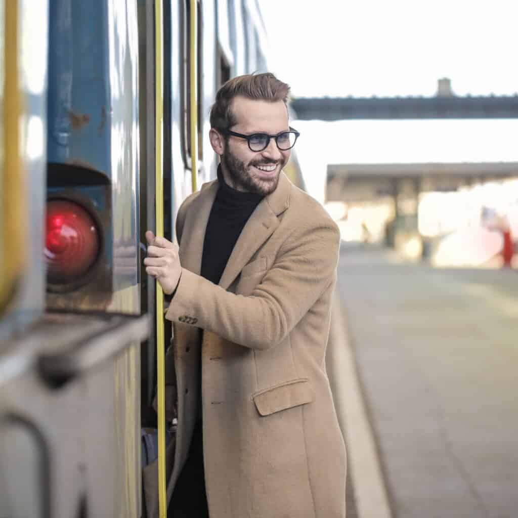 Person stepping onto a train while looking back and smiling.