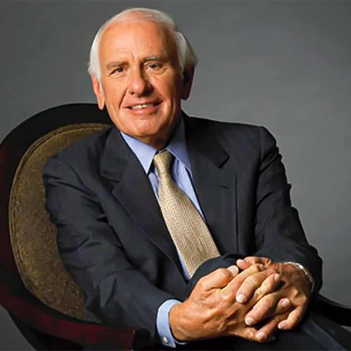 Jim Rohn sitting down with his hands together.