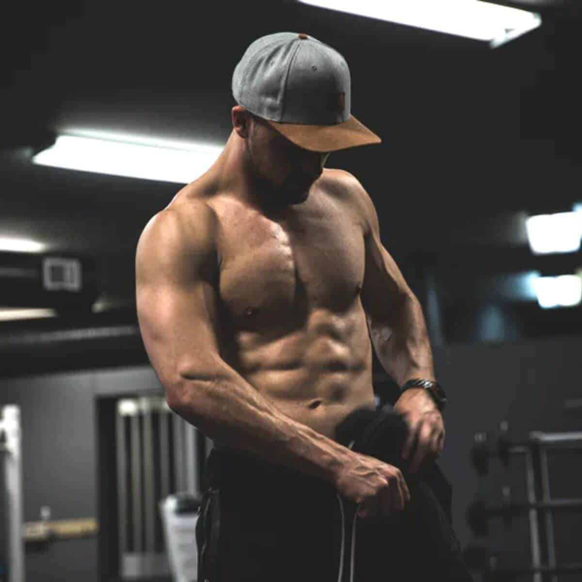 Shirtless person flexing muscles in a gym.