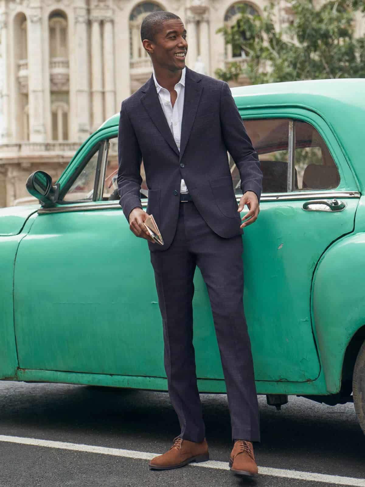 Person in a suit standing in front of a car.