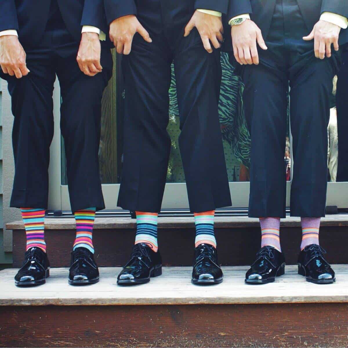 Three people lifting up their trousers to show their socks.