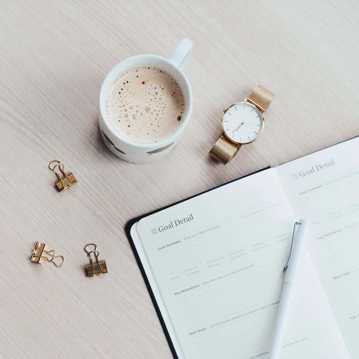 Notebook, coffee, watch, and binder clips.