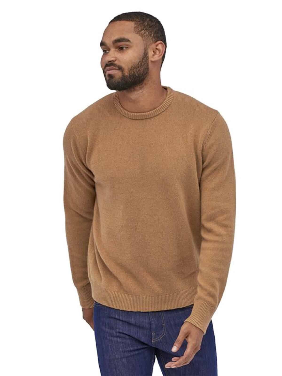 Person wearing a beige sweater and blue jeans.