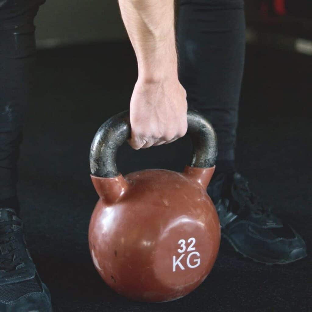 person holding a red kettlebell.