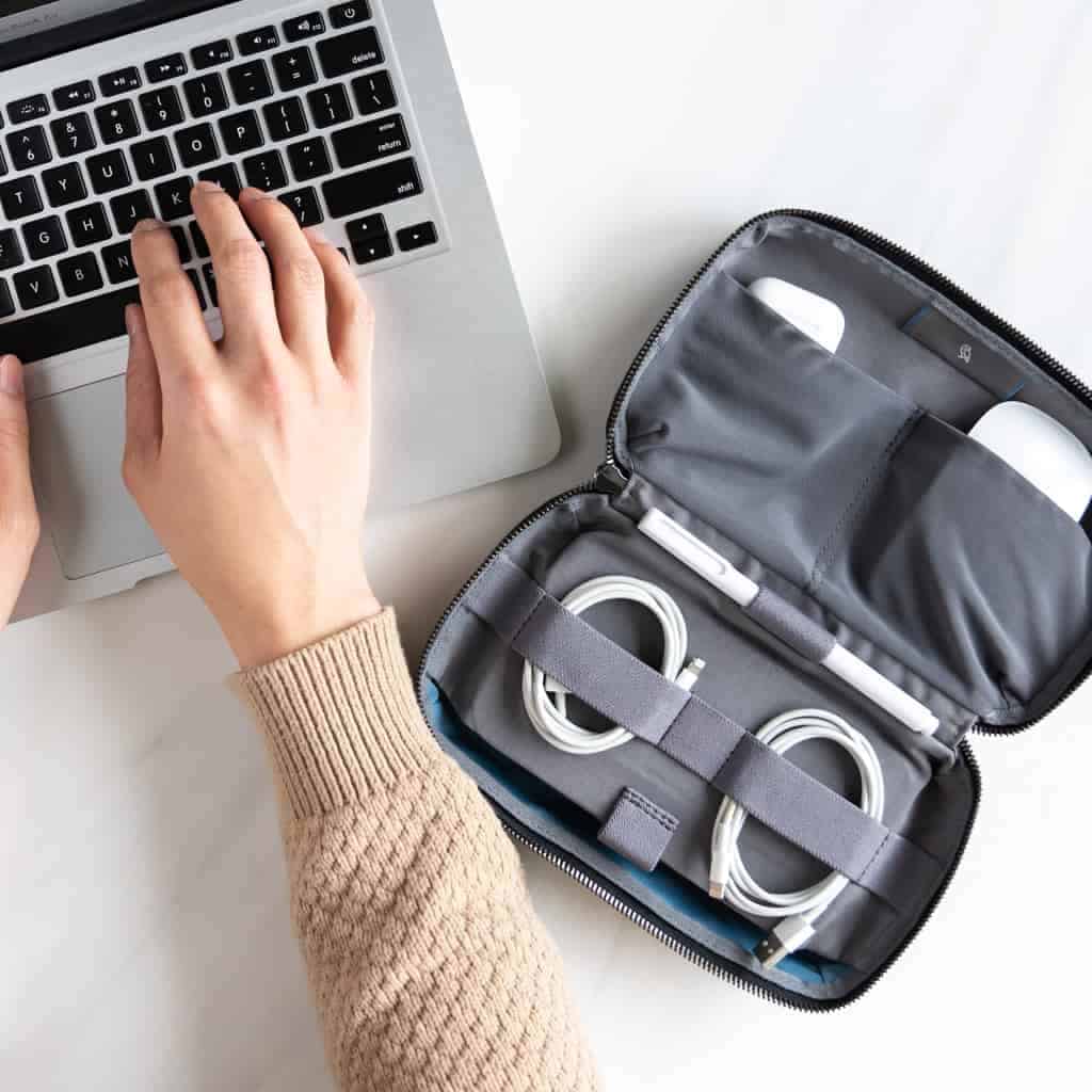 Tech kit organizer next to a person typing on their laptop.