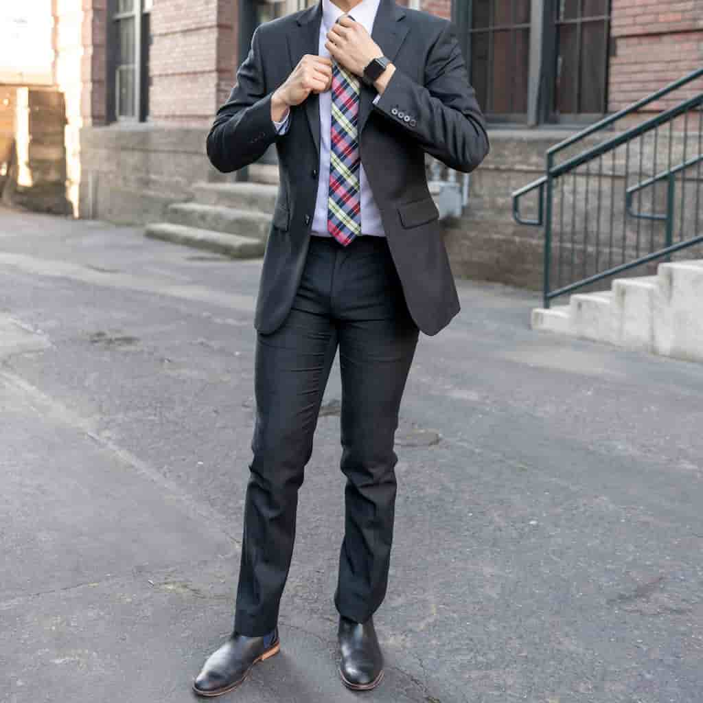 Neck-down of a person wearing a suit with Chelsea boots.