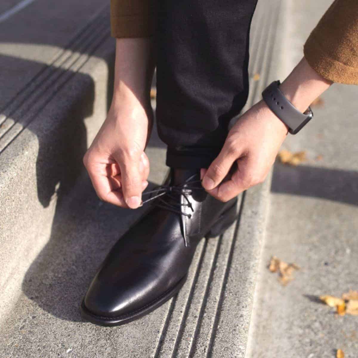 Close-up of a person tying the laces on their chukka boot.