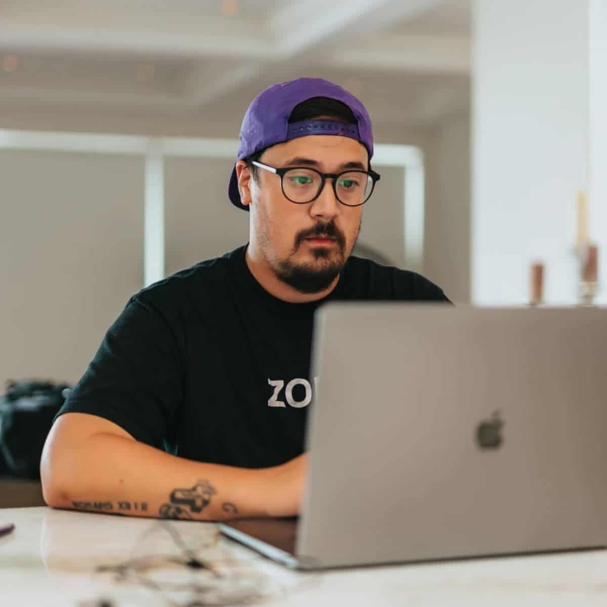 Person wearing glasses and working on their laptop on a table.