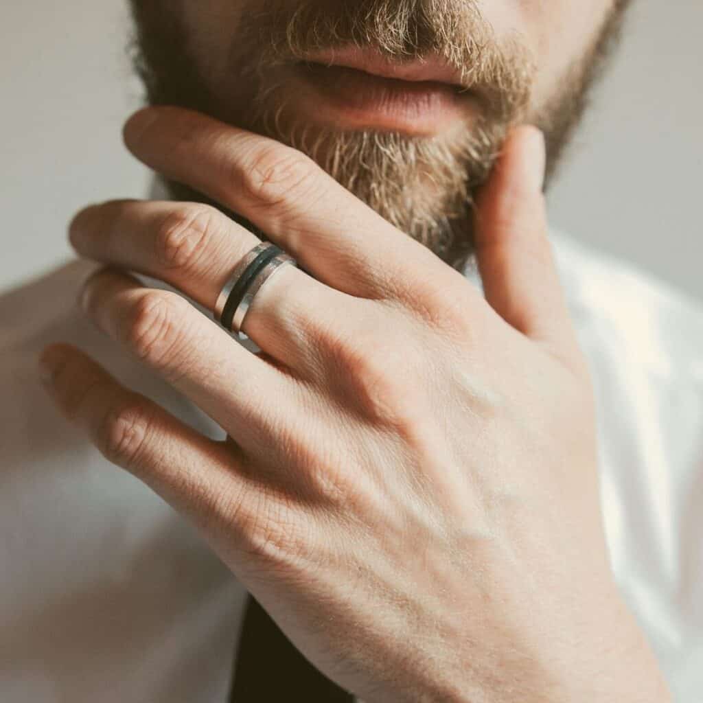 Close-up of a ring on a person's hand while they touch their beard.