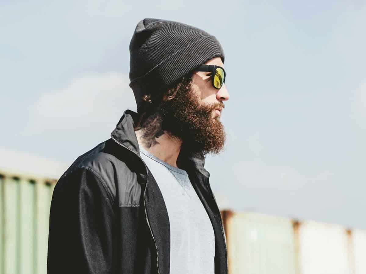 Person wearing a beanie and sunglasses and looking to the side.