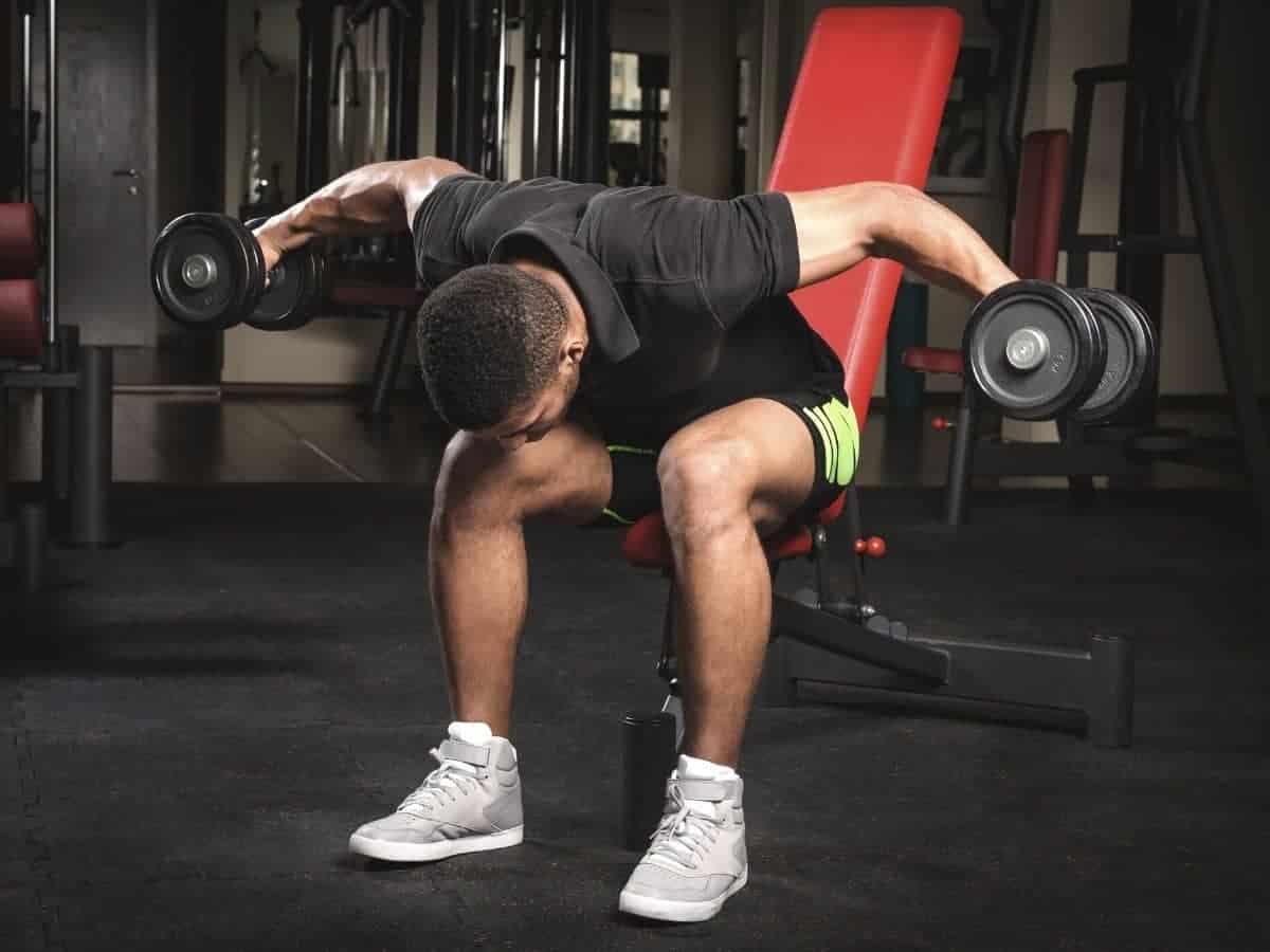 Person doing a reverse fly exercise while sitting on a bench.