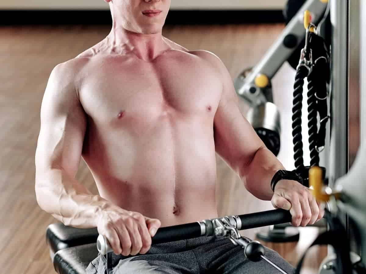 Shirtless person doing a cable row.