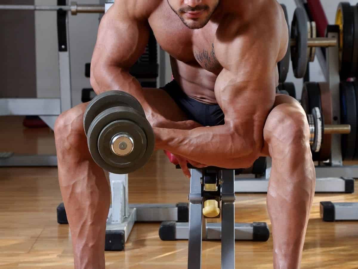 Shirtless person doing concentration curls.