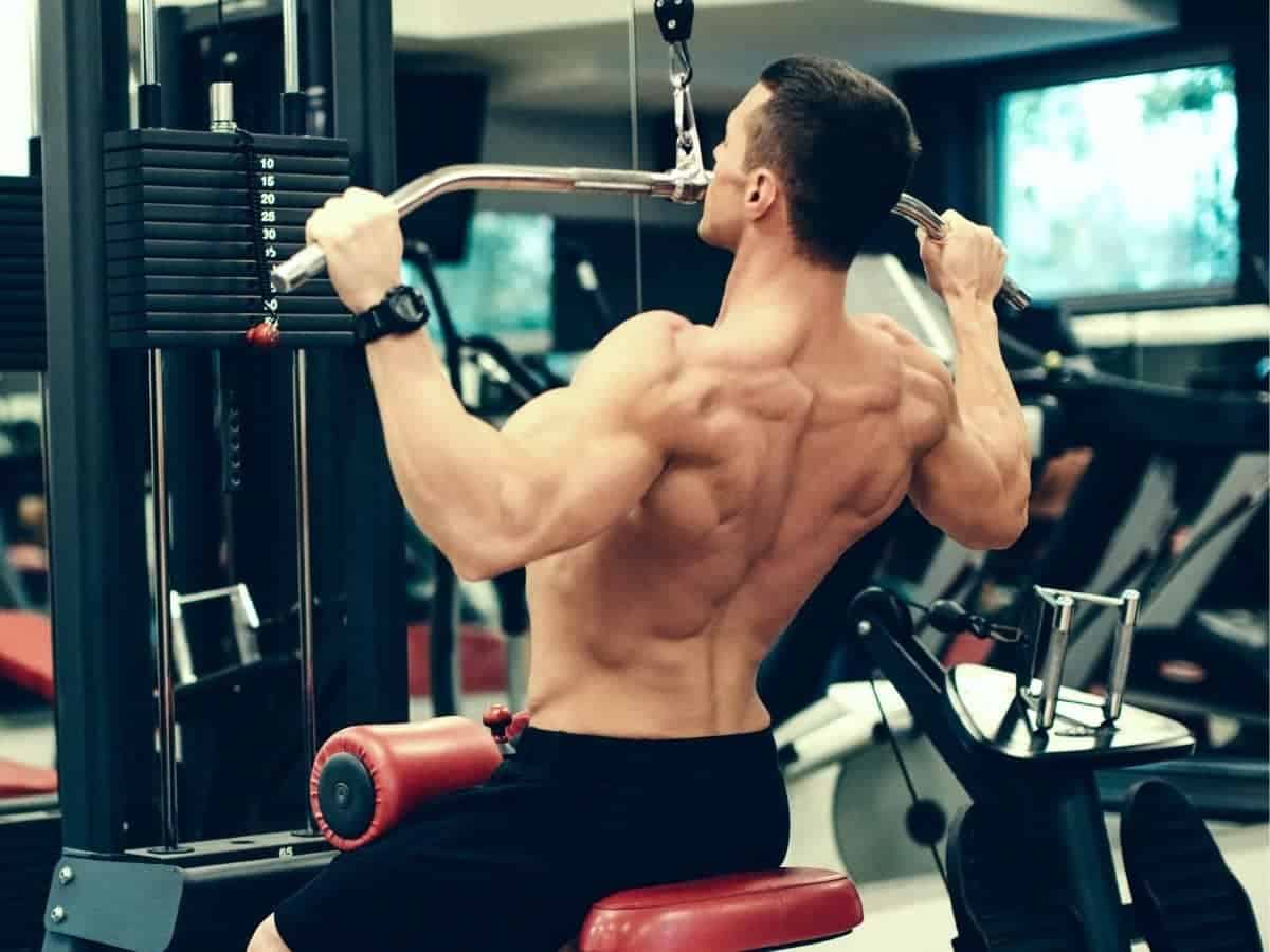 Shirtless person doing a lat pulldown.