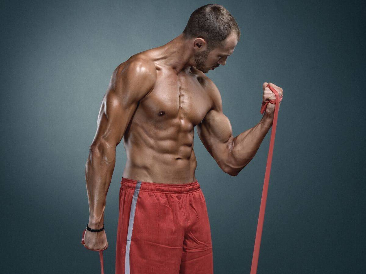 Shirtless person doing resistance band curls.