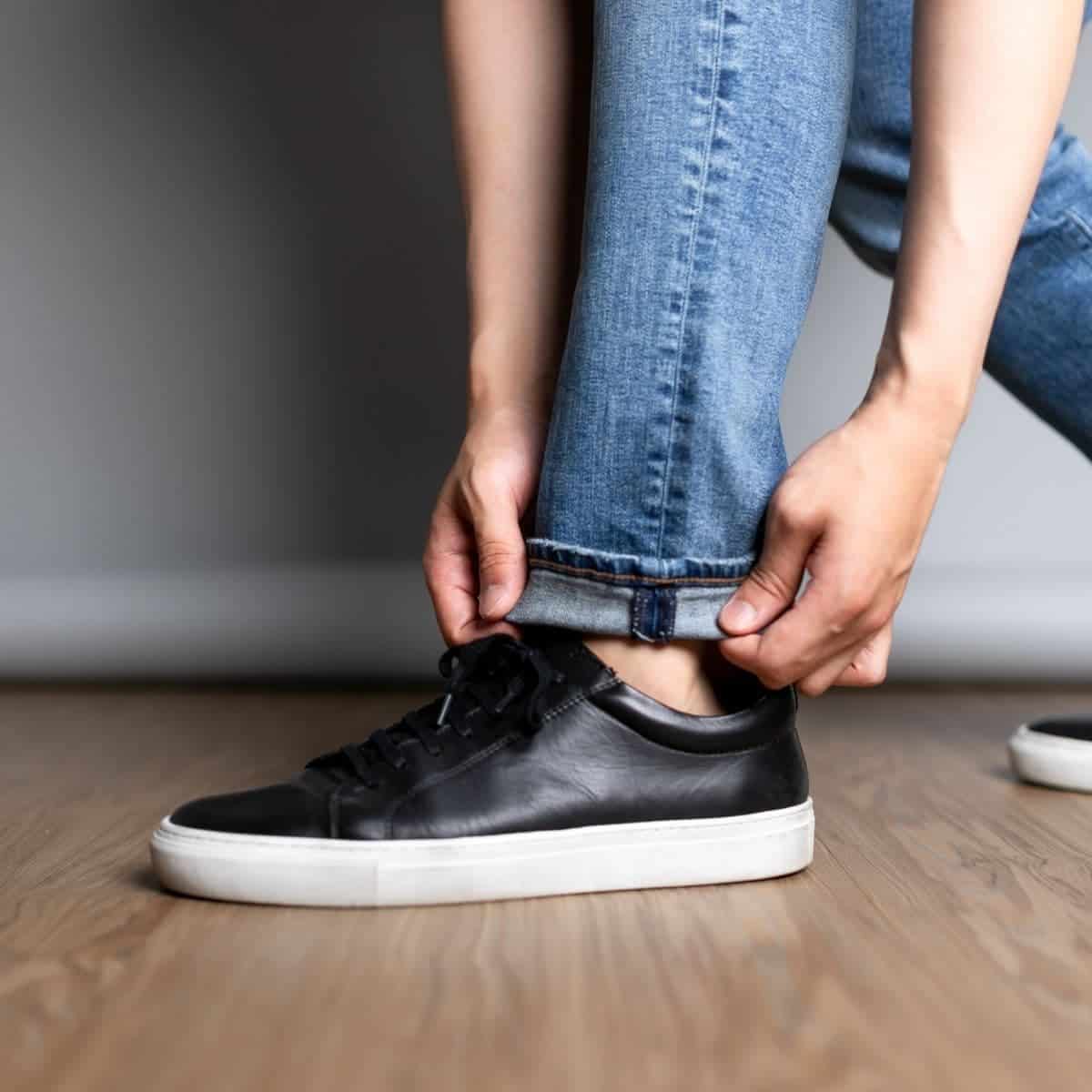 Close-up of a person cuffing their jeans.