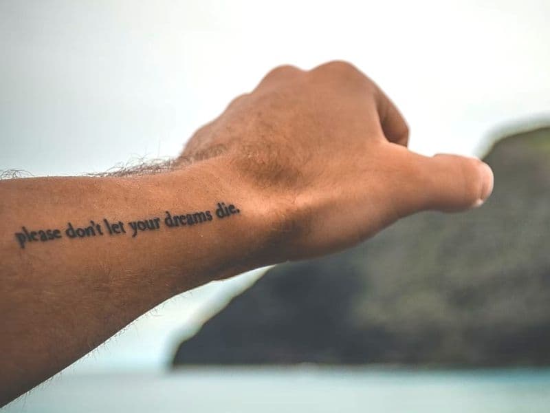 Arm with a quote tattoo.