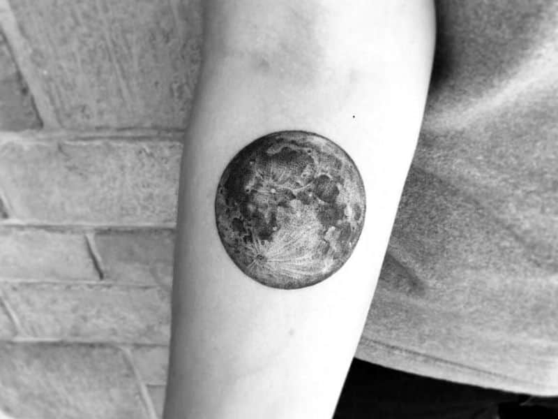 Tattoo of a full moon on a person's arm.