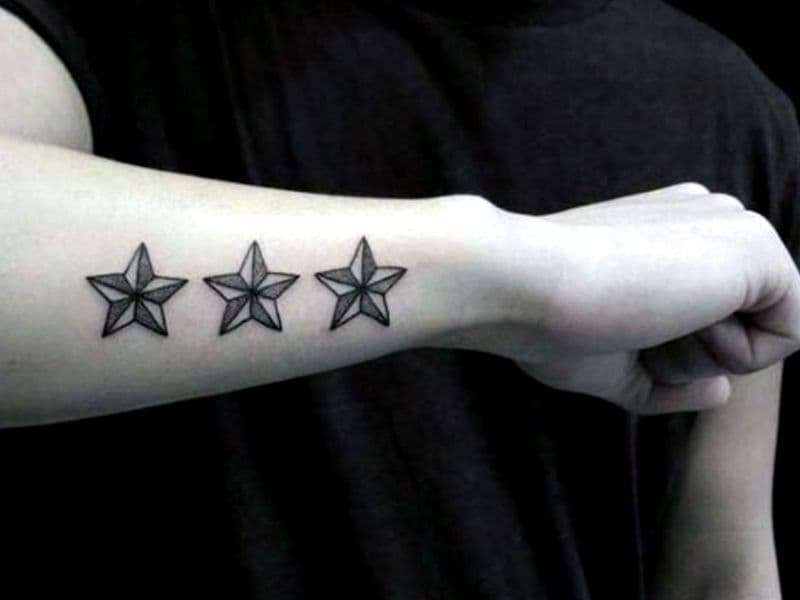 Person's arm with a tattoo of three stars.