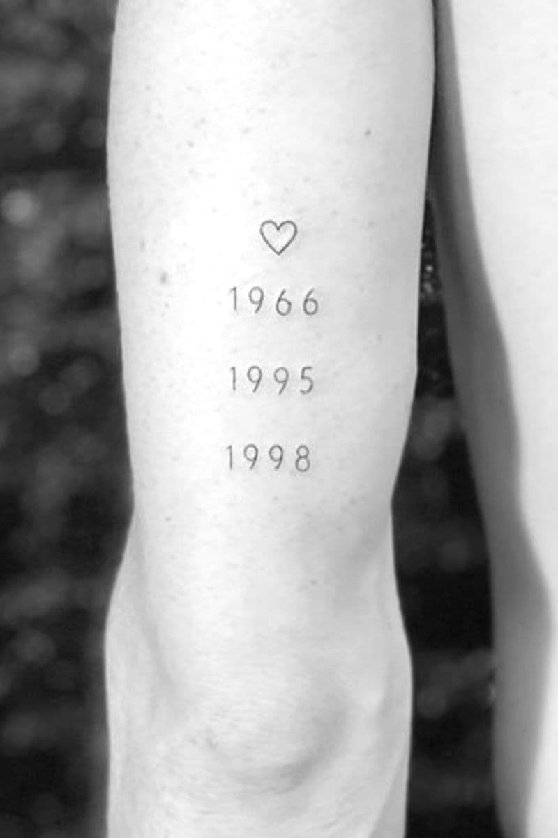 Tattoo of years and a heart on the back of a person's arm.