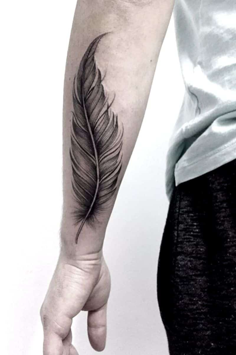 Person's forearm with a feather tattoo.