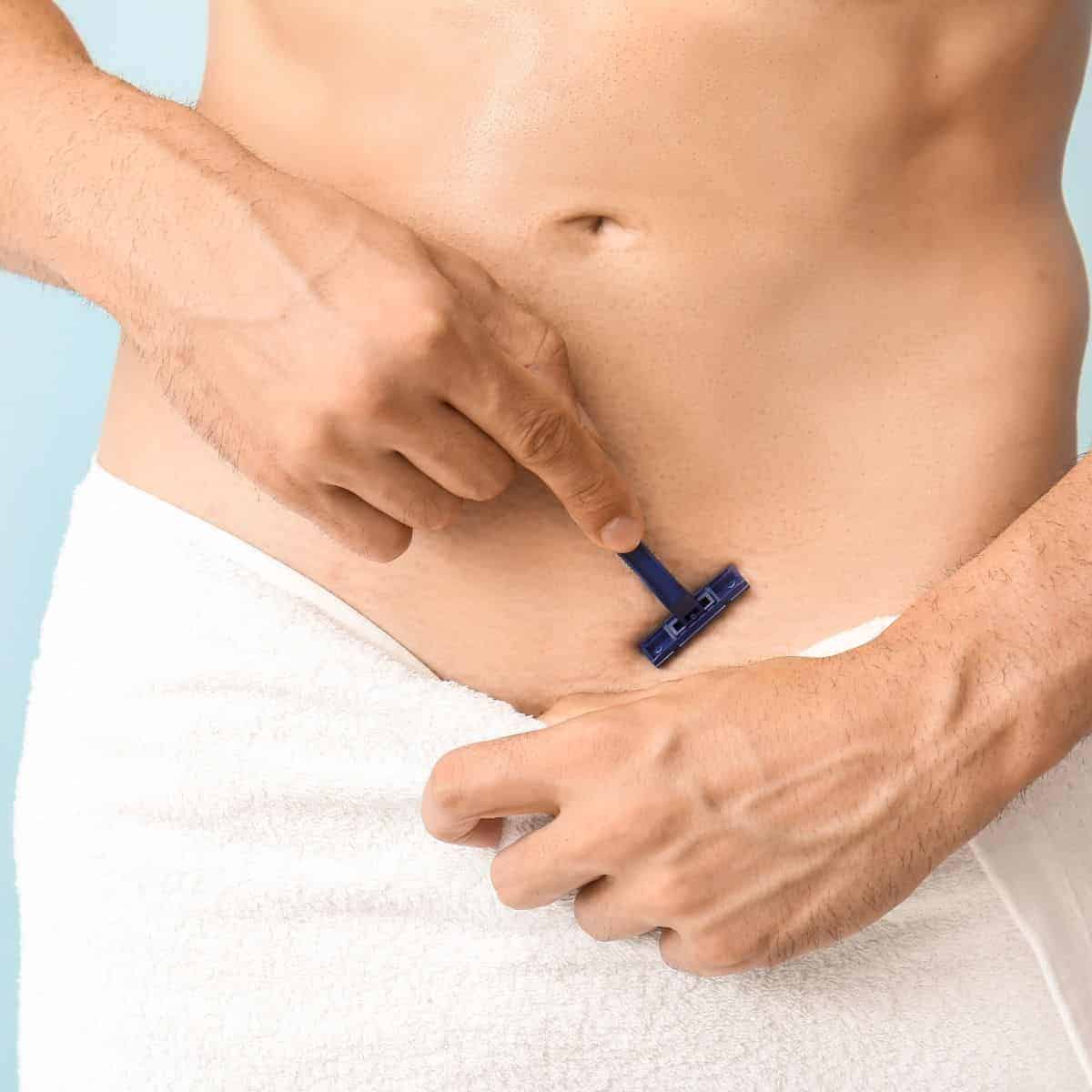 Person wearing a towel and shaving their abdomen.
