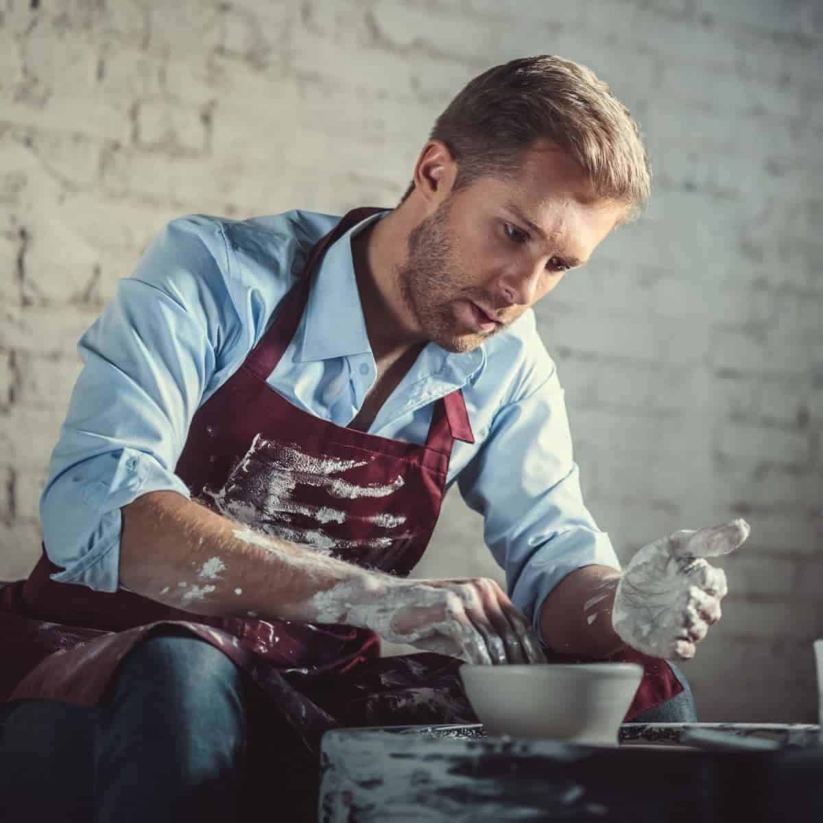 Person sitting and working with clay pottery.