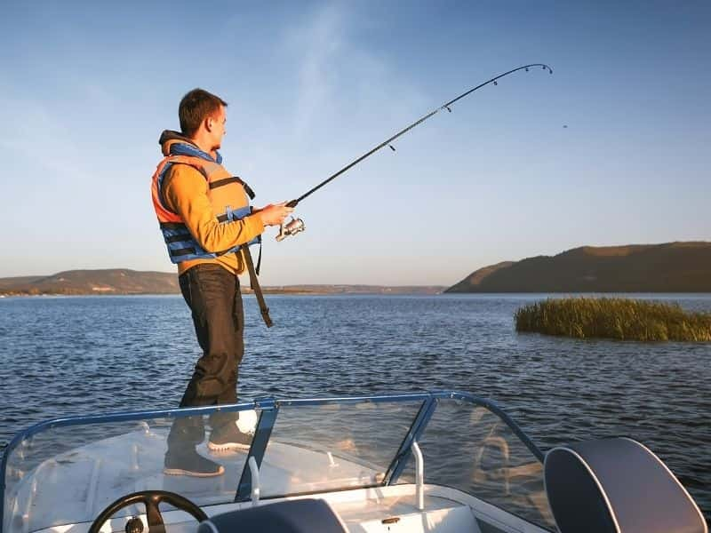 Person fishing on the back of a boat.