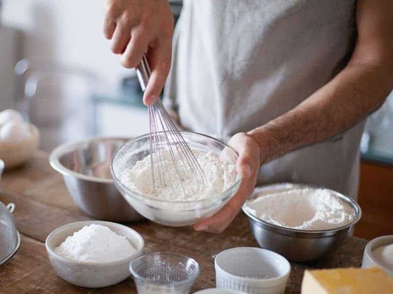 Person mixing flour in a bowl.