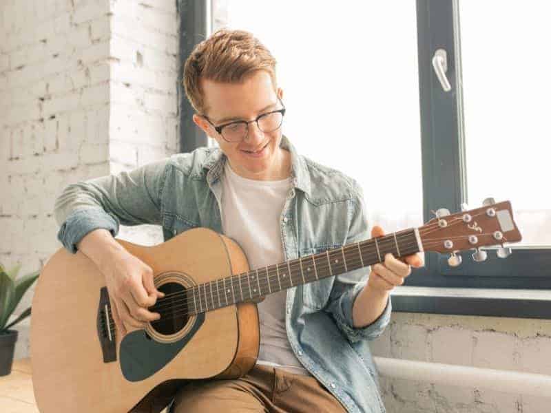 Person playing a guitar in a room.