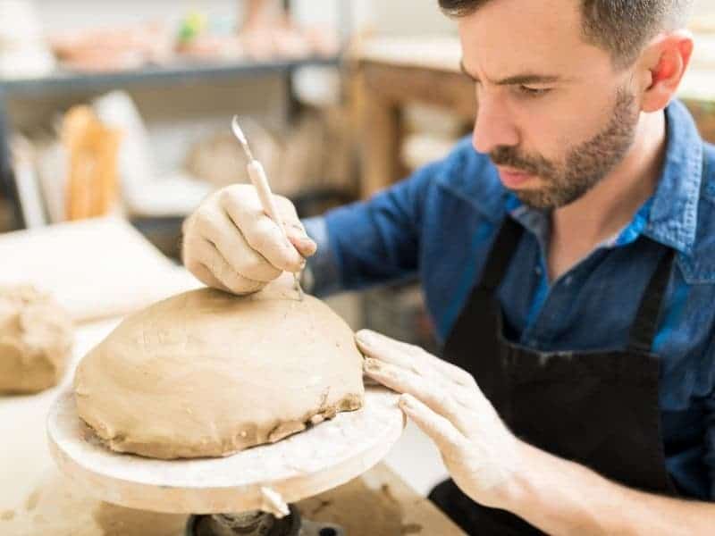 Person using a sculpting tool on clay.