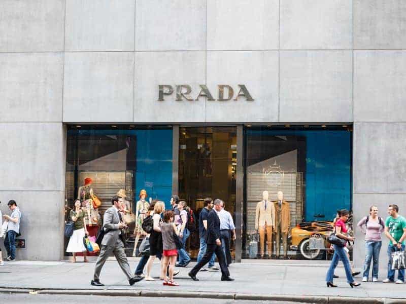 People walking outside of a Prada store.